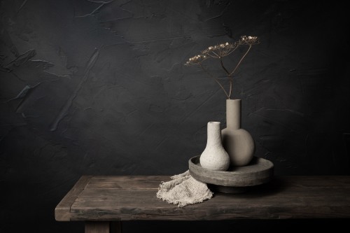 Donker stilleven met gedroogde schermbloem in aardewerk vazen © Mayra Pama