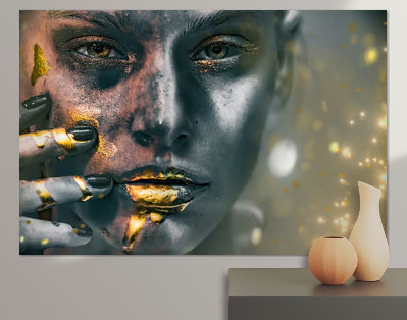 Gouden verfvlekken druipen van het gezicht, de lippen en de hand van de vrouw, lipgloss druipt van sexy lippen, gouden vloeistofdruppels op de mond van een mooi modelmeisje, gouden metalen huidmake-up. Schoonheid vrouw make-up close