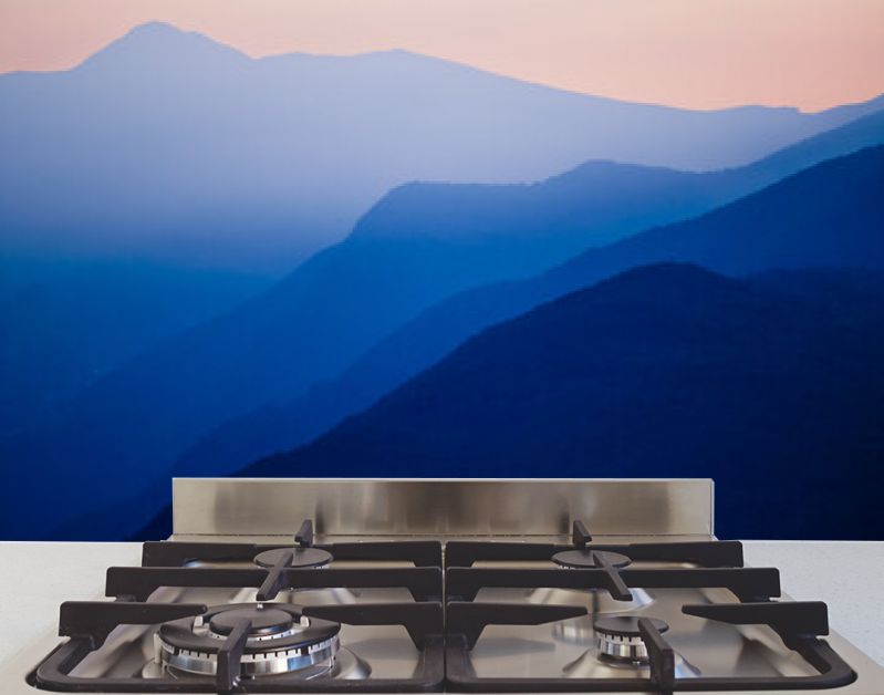 Stacked silhouettes of blue mountains underneath an orange evening sky at Lago Maggiore, Italy close to Switzerland. Original image with minimalist appearance. Ideal background with large copy space.