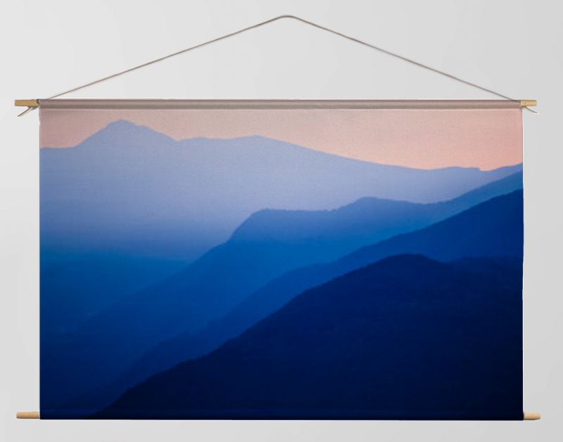Stacked silhouettes of blue mountains underneath an orange evening sky at Lago Maggiore, Italy close to Switzerland. Original image with minimalist appearance. Ideal background with large copy space.