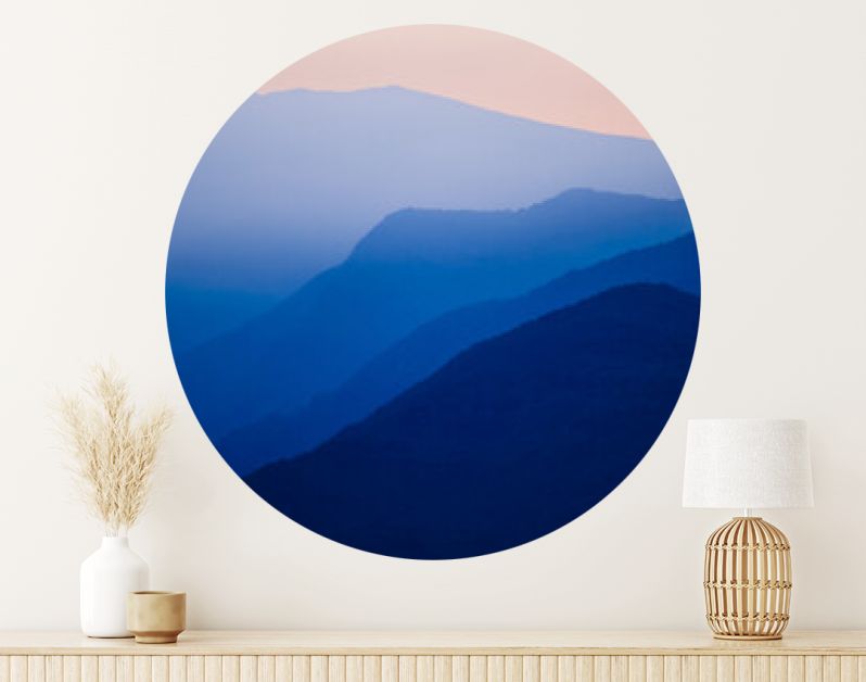 Stacked silhouettes of blue mountains underneath an orange evening sky at Lago Maggiore, Italy close to Switzerland. Original image with minimalist appearance. Ideal background with large copy space.