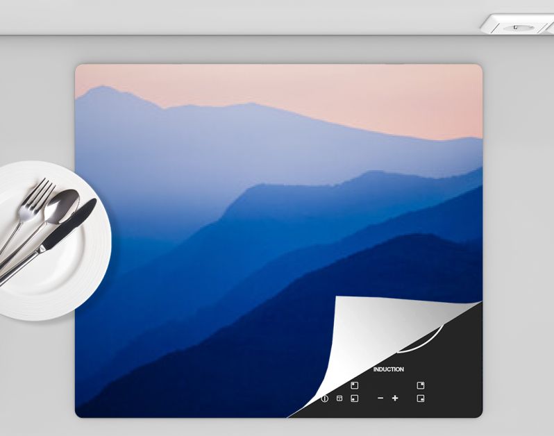 Stacked silhouettes of blue mountains underneath an orange evening sky at Lago Maggiore, Italy close to Switzerland. Original image with minimalist appearance. Ideal background with large copy space.